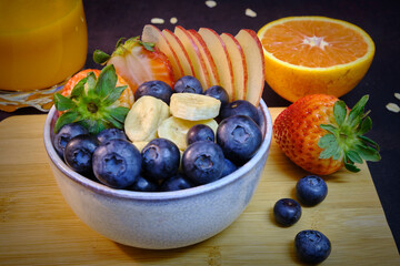 Healthy breakfast with fresh fruits and juice. Bowl of colourful fruits.
