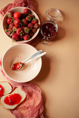 Fresh strawberry in a bowl, strawberry jam and bread for breakfast, flatlay, top view