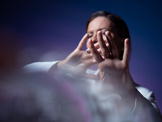 young woman covers her face with her hands, hides and says stop.