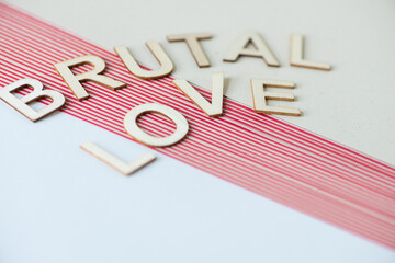 the expression "brutal love" on a pile of plain and striped paper background