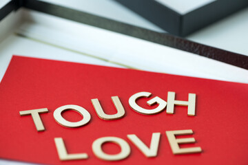 the expression "tough love" on a red paper background - macro lens, shallow depth of field