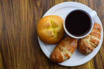 Taza de cafe y pan dulce Guatemalteco, servidos en un plato sobre una mesa de madera, postre guatemalteco.