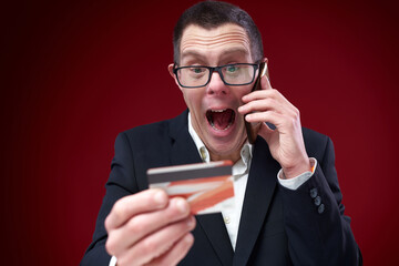 Down syndrome businessman talking on his phone with bank, stunned by his credit card balance
