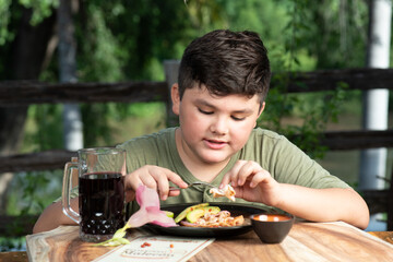 Niño latinoamericano, mexicano, sinaloense comiendo mariscos tostada de camaron acompañado con...