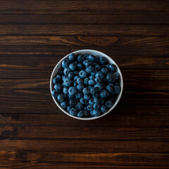 White bowl of blueberries on dark wooden background