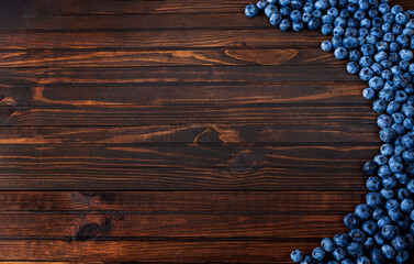 Fresh blueberries on dark wooden background in the shape of a semicircle, top view with copy space.