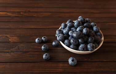 White bowl of blueberries on dark wooden background