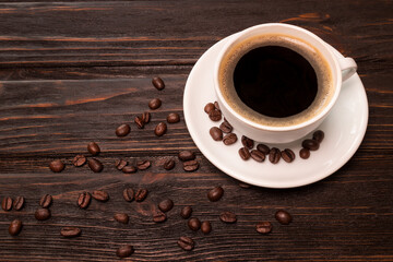 Coffee cup on old wooden table with cofee beans on plate, top view with copy space.