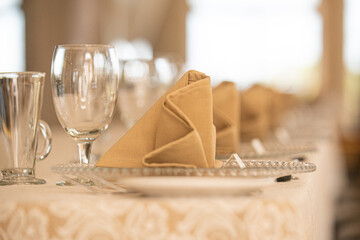 Rows of beige linen folded napklins on glass plates at dinner setting