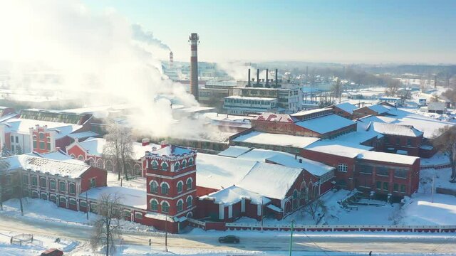 Dobrush, Gomel Region, Belarus. Aerial View Of Old Paper Mill Factory. Bird's-eye View At Sunny Snowy Winter Day 4K. Plant Pipe With Escaping Steam Or Smoke