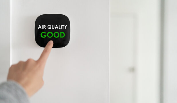 Indoor home air quality smart home domotic automation system. Woman touching touchscreen verifying air purifier filter at GOOD green level banner.