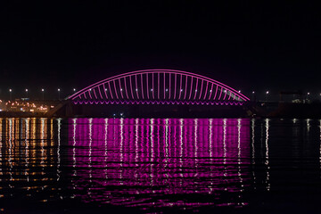Bright night urban bridge reflected in the river
