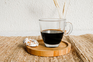 Buttery biscuit with icing sugar on top, and a cup of black coffee. Hard light with sharp shadows. Selective focus.