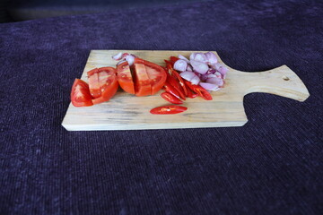 chopped herbs on a wooden cutting board. chili, onion, garlic and tomato