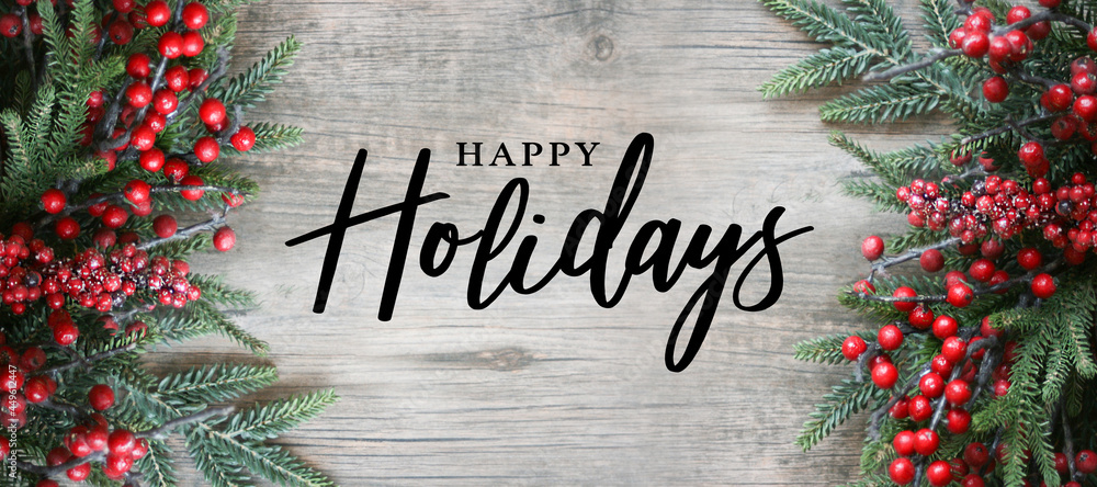 Wall mural happy holidays text with holiday evergreen branches and red berries frame on sides over rustic woode