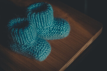 A pair of blue booties for a small child. Early morning, light from the window.