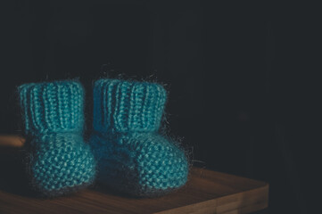 A pair of blue booties for a small child. Early morning, light from the window.