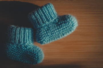 A pair of blue booties for a small child. Early morning, light from the window.