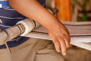 Closeup of hand of a craftsman weaving a tapestry on a wooden loom