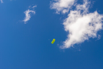 a parachutist under a green canopy of a parachute flies over the audience