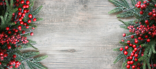 Festive Winter Christmas and New Year Holiday Evergreen Branches and Red Berries Frame on Sides Over Rustic Light Wood Horizontal Background Texture with Copy Space