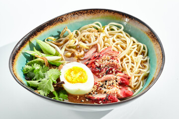 Ramen Chicken Soup - traditional soup with chicken and ramen noodles and other ingredients. Topped with eggs. Ramen soup bowl isolated on white background.