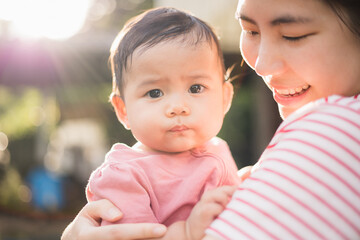 Asian mother holding daughter in arms. She held her daughter in her embrace. Happy asian family child and mom walking outdoor nature. Happy mother's Day