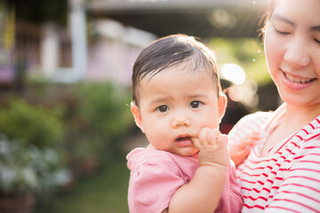 Asian mother holding daughter in arms. She held her daughter in her embrace. Happy asian family child and mom walking outdoor nature. Happy mother's Day