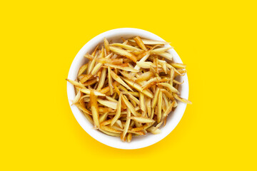 Sliced finger root in white bowl on yellow background.