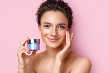 Beautiful woman with jar of moisturizer cream. Photo of woman with perfect skin on pink background. Beauty and Skin care concept