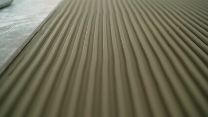 A worker places ceramic floor tiles on an adhesive surface. Home improvement, repair Glue for ceramic tiles. Leveling the adhesive on the floor when laying ceramic tiles.