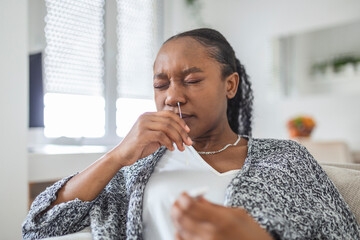Fototapeta na wymiar African-American woman using cotton swab while doing coronavirus PCR test at home. Woman using coronavirus rapid diagnostic test. Young woman at home using a nasal swab for COVID-19.