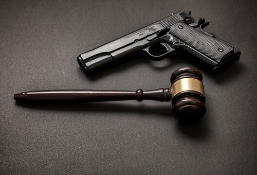 Judge gavel and a 9mm pistol on black background,