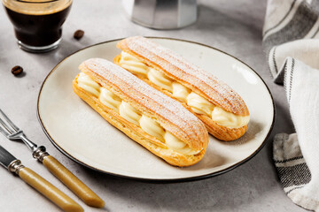 Traditional french eclairs filled with vanilla cream and powdered sugar.