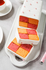 Traditional British Battenberg Cake sliced and served with cup of tea.