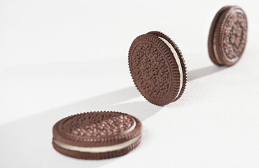 round chocolate cookies on white background. three double layer cookie with vanilla cream filling, selective focus, front view