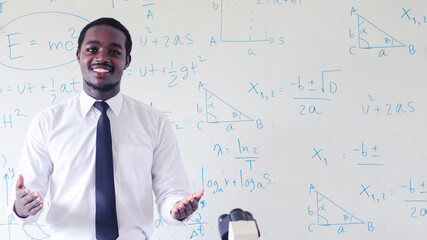 African scientist teacher is teaching science classes with using microscope in the...