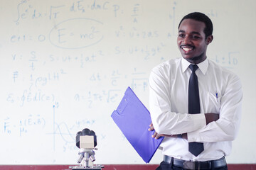 African scientist teacher is teaching science classes with using microscope in the...