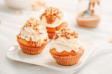 Muffin. Creme muffins with caramel and nuts. Creme on the top of muffin. Caramel muffins.  