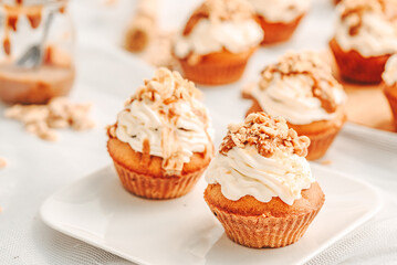 Muffin. Creme muffins with caramel and nuts. Creme on the top of muffin. Caramel muffins.  