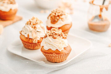 Muffin. Creme muffins with caramel and nuts. Creme on the top of muffin. Caramel muffins.  