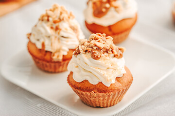 Muffin. Creme muffins with caramel and nuts. Creme on the top of muffin. Caramel muffins.  