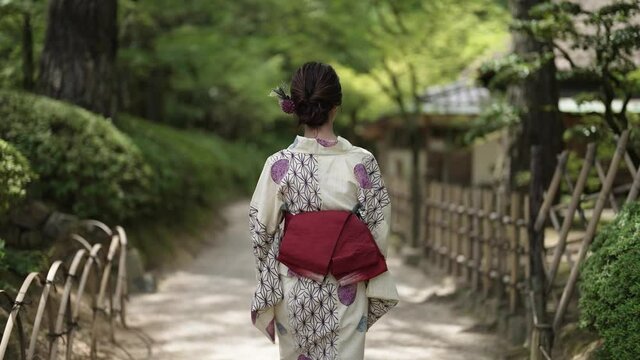 日本庭園を散策する浴衣の女性