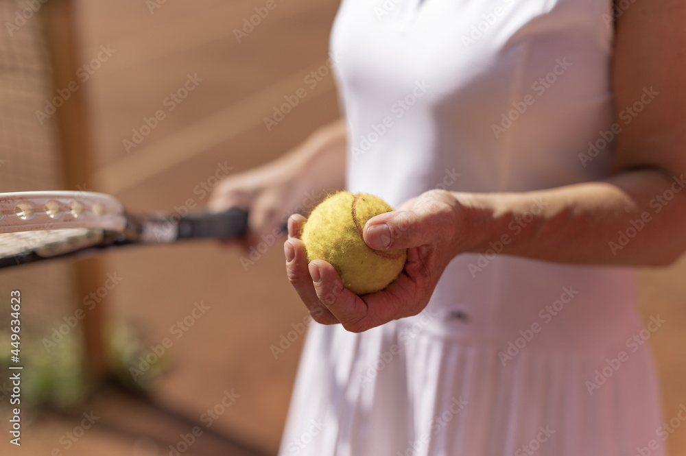 Sticker closeup shot of a female tennis player with white sportswear holding a ball and a racket