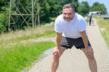 Happy healthy man taking a rest while out jogging