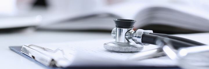 Stethoscope head lying on medical forms closeup