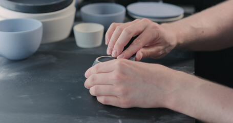 Fototapeta na wymiar man hands polishing bottom of black ceramic cup