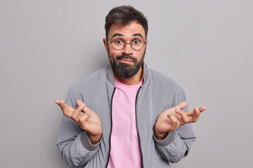 Clueless bearded man shrugs shoulders looks puzzled and unaware say I dont understand wears round...