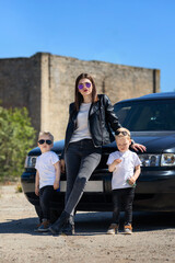Mom and the twins in leather jackets and sunglasses.A bold and cool family image.Blonde little twin...
