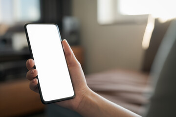 Young woman hold smartphone with white screen while sitting on a couch